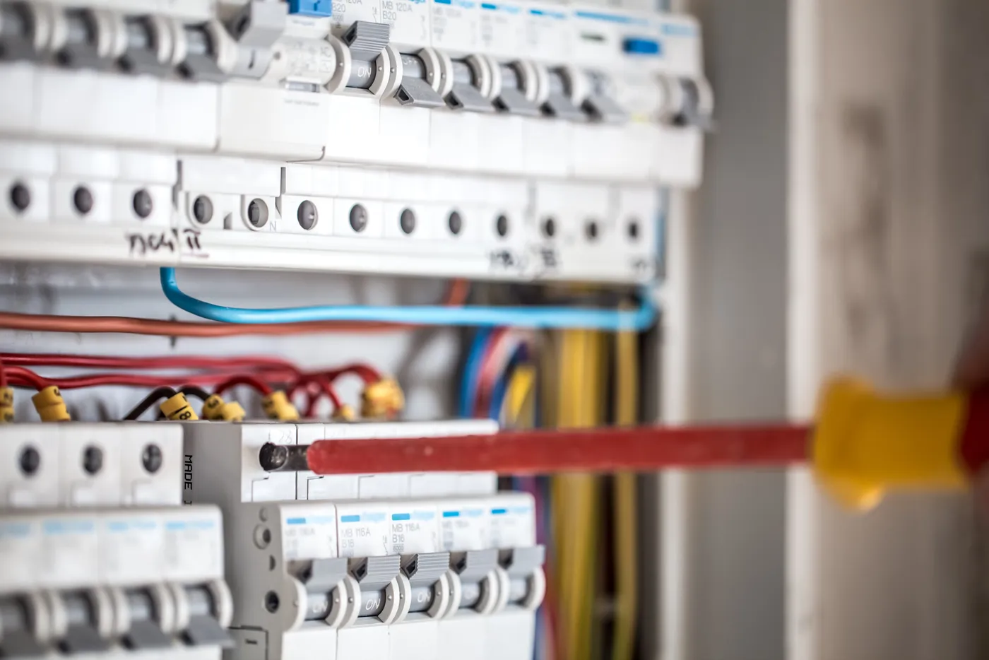 Técnico eletricista inspecionando um quadro de distribuição com disjuntores